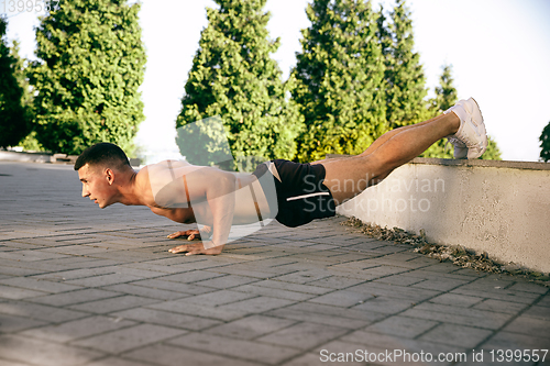 Image of A male athlete doing workout on the city\'s street or park