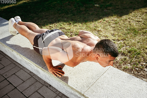 Image of A male athlete doing workout on the city\'s street or park