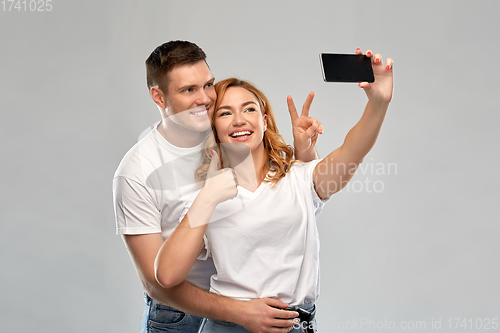 Image of happy couple in white t-shirts taking selfie