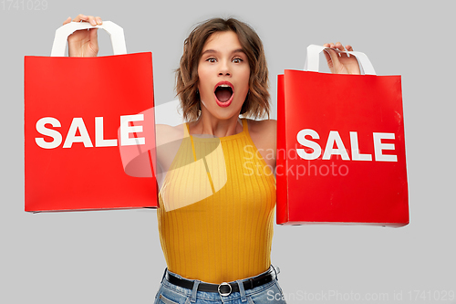 Image of surprised young woman with shopping bags on sale