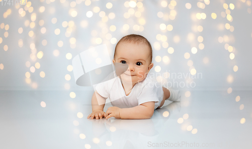 Image of sweet little baby lying on floor over lights