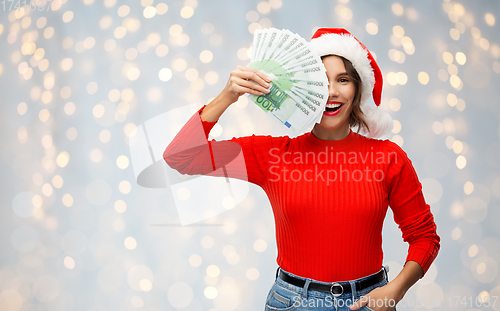 Image of happy woman in santa hat with money on christmas