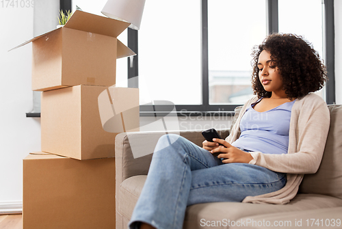 Image of woman with smartphone and boxes moving to new home