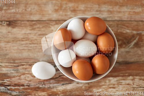 Image of close up of eggs in ceramic bowl on wooden table