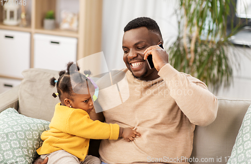Image of father with baby at home calling on smartphone