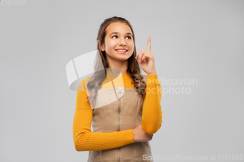 Image of smiling young teenage girl pointing finger up