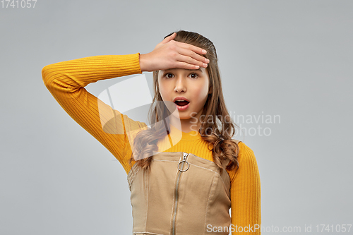 Image of shocked young teenage girl holding to her head