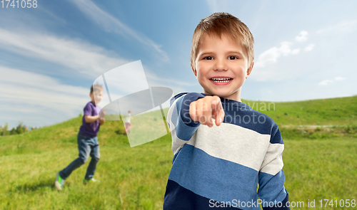 Image of little boy pointing finger to camera outdoors