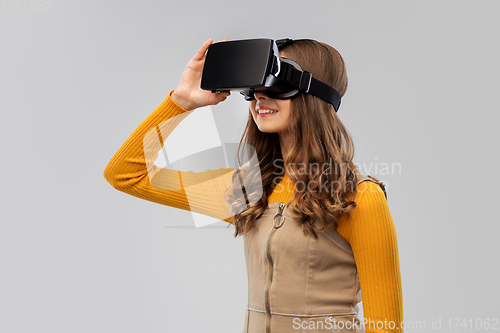 Image of teenage girl in vr glasses over grey background