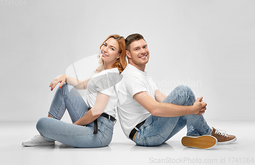 Image of happy couple in white t-shirts sitting on floor