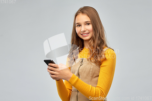 Image of smiling teenage girl using smartphone