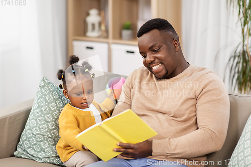 Image of african father reading book for baby daughter