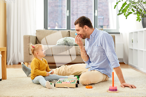 Image of father playing with little baby daughter at home