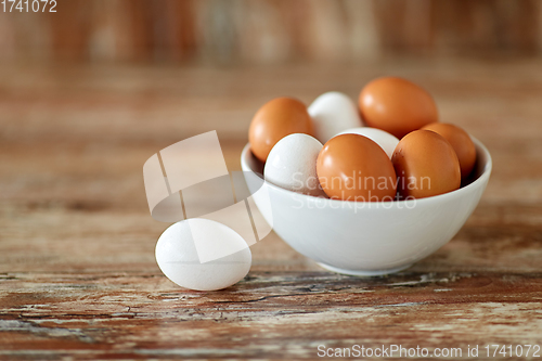 Image of close up of eggs in ceramic bowl on wooden table