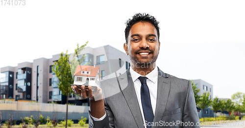 Image of indian man realtor with house model on city street