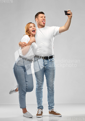 Image of happy couple in white t-shirts taking selfie