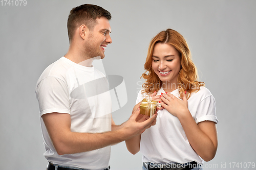 Image of happy couple in white t-shirts with christmas gift