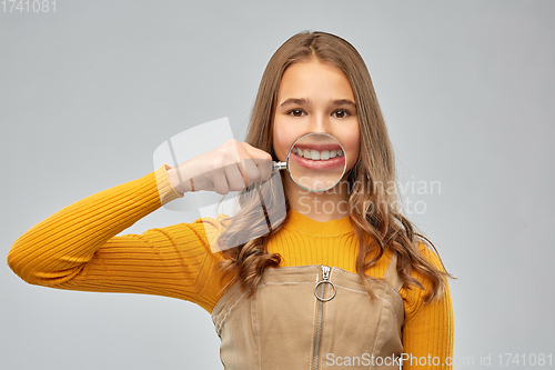 Image of teenage girl shows teeth through magnifying glass