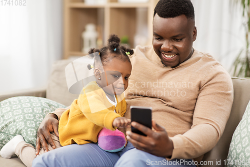 Image of father with smartphone and baby daugter at home