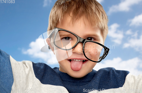 Image of portrait of little boy in glasses showing tongue