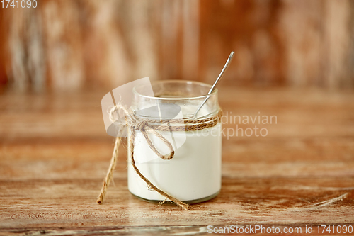 Image of yogurt or sour cream in glass jar on wooden table