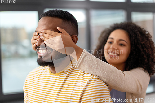 Image of happy african american woman closing man\'s eyes