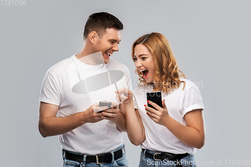 Image of happy couple in white t-shirts with smartphones