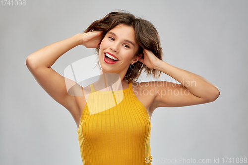 Image of happy laughing young woman in mustard yellow top