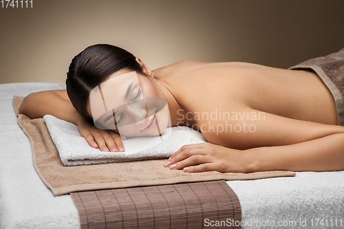 Image of young woman lying at spa or massage parlor