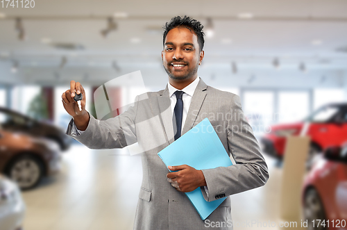 Image of happy indian car dealer with car key at showroom