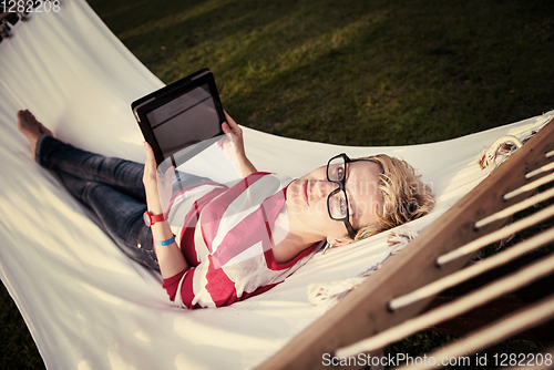 Image of woman using a tablet computer while relaxing on hammock