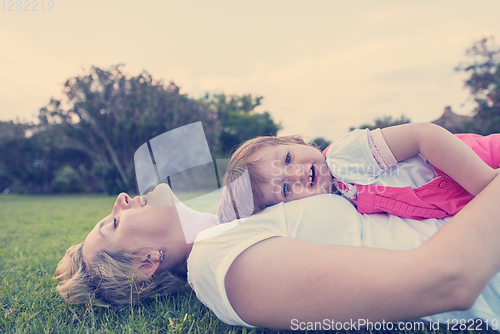 Image of mother and little daughter playing at backyard