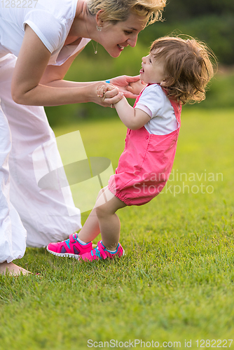 Image of mother and little daughter playing at backyard