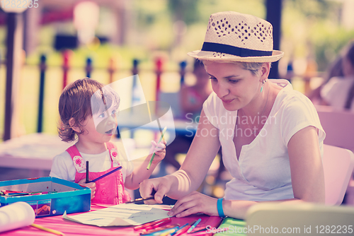 Image of mom and little daughter drawing a colorful pictures