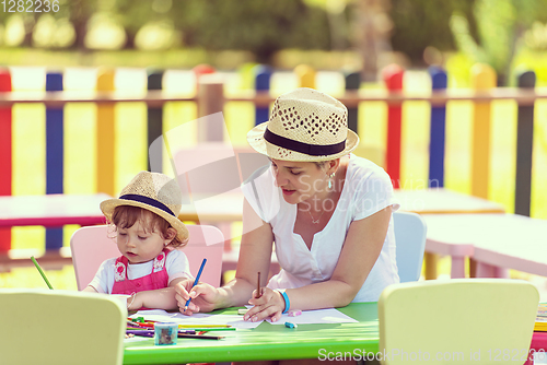 Image of mom and little daughter drawing a colorful pictures