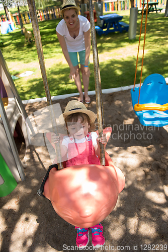 Image of mother and daughter swinging in the park