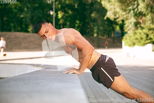 Image of A male athlete doing workout on the city\'s street or park