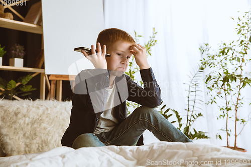 Image of Little boy using different gadgets at home