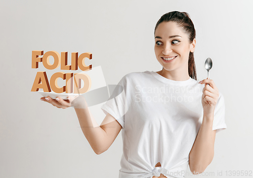 Image of Food concept. Model holding a plate with letters of Folic Acid