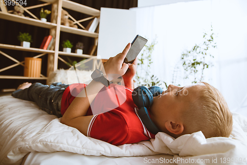 Image of Little boy using different gadgets at home