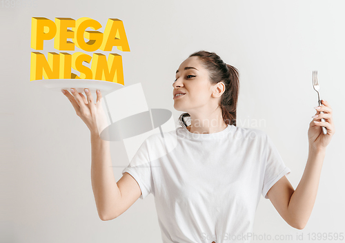 Image of Food concept. Model holding a plate with letters of Peganism