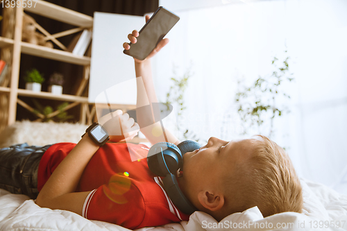 Image of Little boy using different gadgets at home