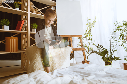 Image of Little boy using different gadgets at home
