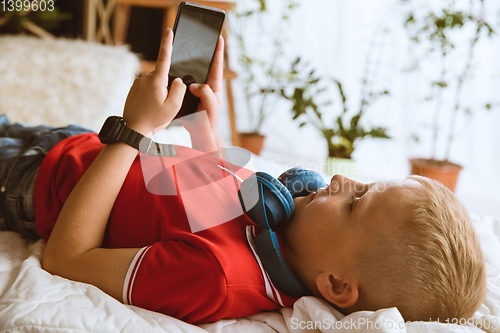 Image of Little boy using different gadgets at home