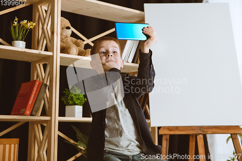 Image of Little boy using different gadgets at home