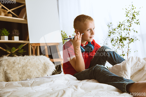 Image of Little boy using different gadgets at home