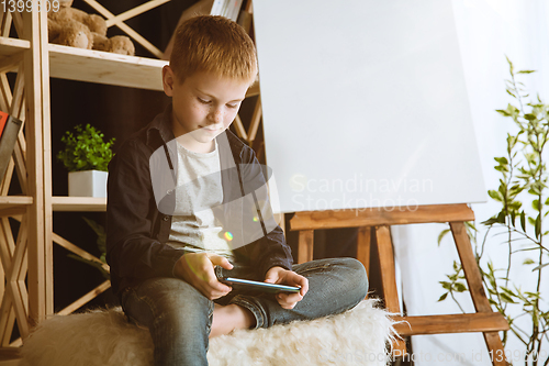 Image of Little boy using different gadgets at home