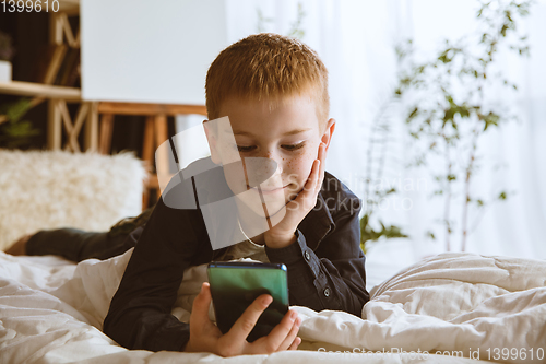 Image of Little boy using different gadgets at home