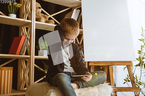 Image of Little boy using different gadgets at home