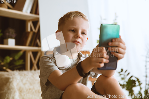 Image of Little boy using different gadgets at home